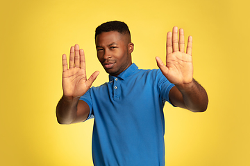 Image showing Young african-american man\'s portrait isolated on yellow studio background, facial expression. Beautiful male half-lenght portrait with copyspace.