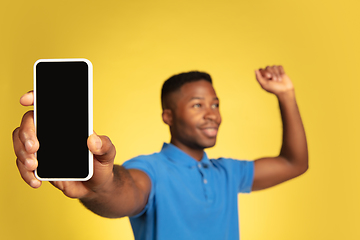 Image showing Young african-american man\'s portrait isolated on yellow studio background, facial expression. Beautiful male half-lenght portrait with copyspace.