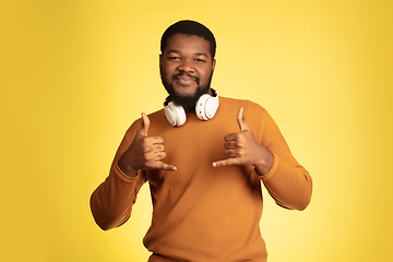 Image showing Young african-american man\'s portrait isolated on yellow studio background, facial expression. Beautiful male half-lenght portrait with copyspace.