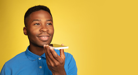 Image showing Young african-american man\'s portrait isolated on yellow studio background, facial expression. Beautiful male half-lenght portrait with copyspace.