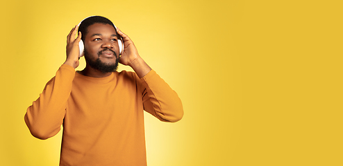 Image showing Young african-american man\'s portrait isolated on yellow studio background, facial expression. Beautiful male half-lenght portrait with copyspace.