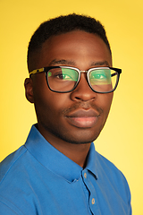 Image showing Young african-american man\'s portrait isolated on yellow studio background, facial expression. Beautiful male half-lenght portrait with copyspace.