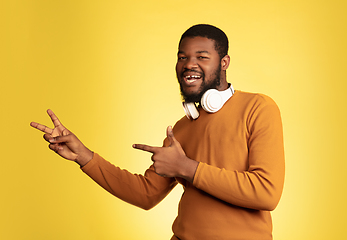 Image showing Young african-american man\'s portrait isolated on yellow studio background, facial expression. Beautiful male half-lenght portrait with copyspace.