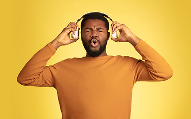 Image showing Young african-american man\'s portrait isolated on yellow studio background, facial expression. Beautiful male half-lenght portrait with copyspace.