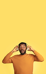 Image showing Young african-american man\'s portrait isolated on yellow studio background, facial expression. Beautiful male half-lenght portrait with copyspace.