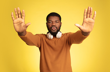 Image showing Young african-american man\'s portrait isolated on yellow studio background, facial expression. Beautiful male half-lenght portrait with copyspace.