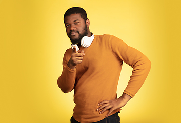 Image showing Young african-american man\'s portrait isolated on yellow studio background, facial expression. Beautiful male half-lenght portrait with copyspace.