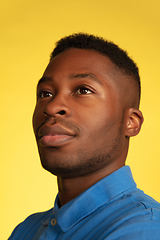 Image showing Young african-american man\'s portrait isolated on yellow studio background, facial expression. Beautiful male half-lenght portrait with copyspace.