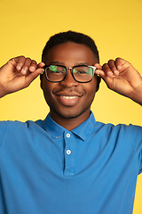 Image showing Young african-american man\'s portrait isolated on yellow studio background, facial expression. Beautiful male half-lenght portrait with copyspace.