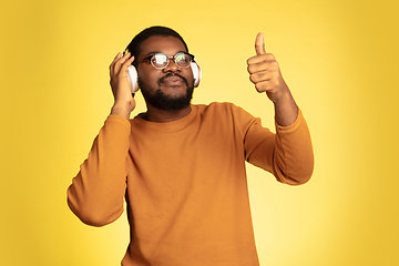 Image showing Young african-american man\'s portrait isolated on yellow studio background, facial expression. Beautiful male half-lenght portrait with copyspace.