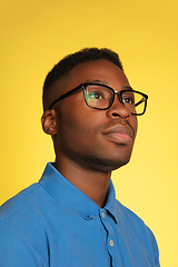 Image showing Young african-american man\'s portrait isolated on yellow studio background, facial expression. Beautiful male half-lenght portrait with copyspace.