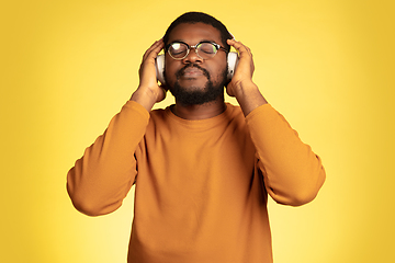 Image showing Young african-american man\'s portrait isolated on yellow studio background, facial expression. Beautiful male half-lenght portrait with copyspace.