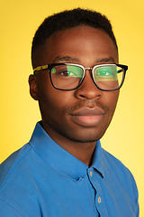 Image showing Young african-american man\'s portrait isolated on yellow studio background, facial expression. Beautiful male half-lenght portrait with copyspace.