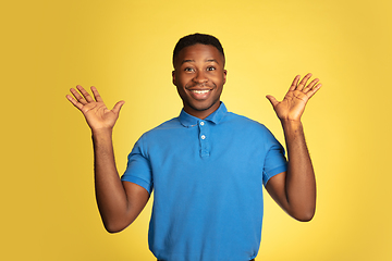 Image showing Young african-american man\'s portrait isolated on yellow studio background, facial expression. Beautiful male half-lenght portrait with copyspace.