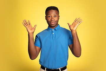 Image showing Young african-american man\'s portrait isolated on yellow studio background, facial expression. Beautiful male half-lenght portrait with copyspace.