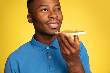 Image showing Young african-american man\'s portrait isolated on yellow studio background, facial expression. Beautiful male half-lenght portrait with copyspace.