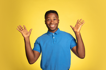 Image showing Young african-american man\'s portrait isolated on yellow studio background, facial expression. Beautiful male half-lenght portrait with copyspace.