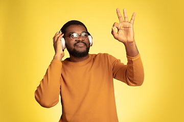 Image showing Young african-american man\'s portrait isolated on yellow studio background, facial expression. Beautiful male half-lenght portrait with copyspace.