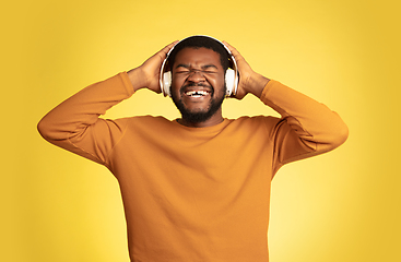 Image showing Young african-american man\'s portrait isolated on yellow studio background, facial expression. Beautiful male half-lenght portrait with copyspace.