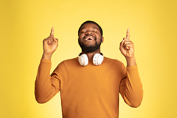 Image showing Young african-american man\'s portrait isolated on yellow studio background, facial expression. Beautiful male half-lenght portrait with copyspace.