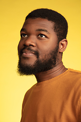 Image showing Young african-american man\'s portrait isolated on yellow studio background, facial expression. Beautiful male half-lenght portrait with copyspace.