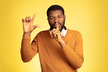 Image showing Young african-american man\'s portrait isolated on yellow studio background, facial expression. Beautiful male half-lenght portrait with copyspace.