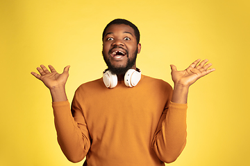 Image showing Young african-american man\'s portrait isolated on yellow studio background, facial expression. Beautiful male half-lenght portrait with copyspace.