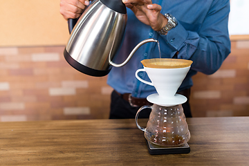 Image showing Barista pouring water on coffee with filter in cafe