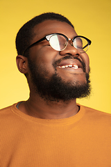 Image showing Young african-american man\'s portrait isolated on yellow studio background, facial expression. Beautiful male half-lenght portrait with copyspace.