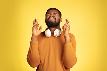 Image showing Young african-american man\'s portrait isolated on yellow studio background, facial expression. Beautiful male half-lenght portrait with copyspace.