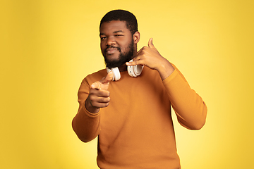 Image showing Young african-american man\'s portrait isolated on yellow studio background, facial expression. Beautiful male half-lenght portrait with copyspace.