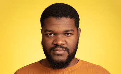 Image showing Young african-american man\'s portrait isolated on yellow studio background, facial expression. Beautiful male half-lenght portrait with copyspace.