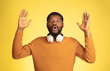 Image showing Young african-american man\'s portrait isolated on yellow studio background, facial expression. Beautiful male half-lenght portrait with copyspace.