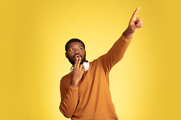 Image showing Young african-american man\'s portrait isolated on yellow studio background, facial expression. Beautiful male half-lenght portrait with copyspace.