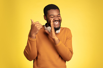 Image showing Young african-american man\'s portrait isolated on yellow studio background, facial expression. Beautiful male half-lenght portrait with copyspace.