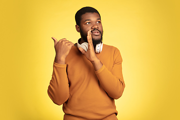 Image showing Young african-american man\'s portrait isolated on yellow studio background, facial expression. Beautiful male half-lenght portrait with copyspace.