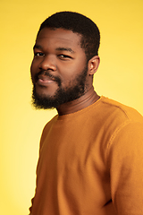 Image showing Young african-american man\'s portrait isolated on yellow studio background, facial expression. Beautiful male half-lenght portrait with copyspace.