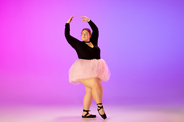 Image showing Beautiful caucasian plus size model practicing ballet dance on gradient purple-pink studio background in neon light