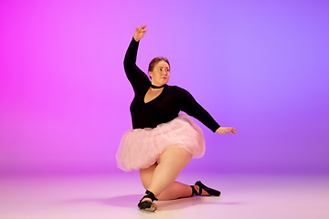 Image showing Beautiful caucasian plus size model practicing ballet dance on gradient purple-pink studio background in neon light