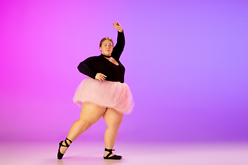 Image showing Beautiful caucasian plus size model practicing ballet dance on gradient purple-pink studio background in neon light