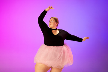 Image showing Beautiful caucasian plus size model practicing ballet dance on gradient purple-pink studio background in neon light