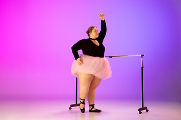 Image showing Beautiful caucasian plus size model practicing ballet dance on gradient purple-pink studio background in neon light