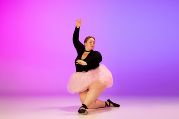 Image showing Beautiful caucasian plus size model practicing ballet dance on gradient purple-pink studio background in neon light