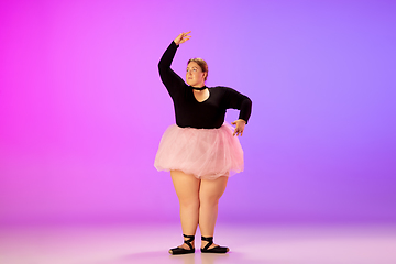 Image showing Beautiful caucasian plus size model practicing ballet dance on gradient purple-pink studio background in neon light