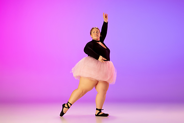 Image showing Beautiful caucasian plus size model practicing ballet dance on gradient purple-pink studio background in neon light