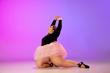 Image showing Beautiful caucasian plus size model practicing ballet dance on gradient purple-pink studio background in neon light