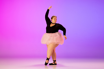 Image showing Beautiful caucasian plus size model practicing ballet dance on gradient purple-pink studio background in neon light