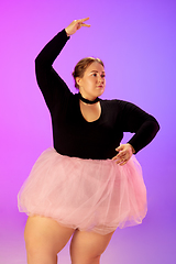 Image showing Beautiful caucasian plus size model practicing ballet dance on gradient purple-pink studio background in neon light