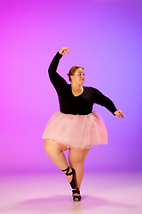 Image showing Beautiful caucasian plus size model practicing ballet dance on gradient purple-pink studio background in neon light