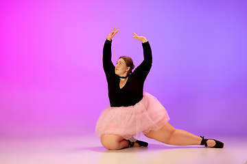 Image showing Beautiful caucasian plus size model practicing ballet dance on gradient purple-pink studio background in neon light